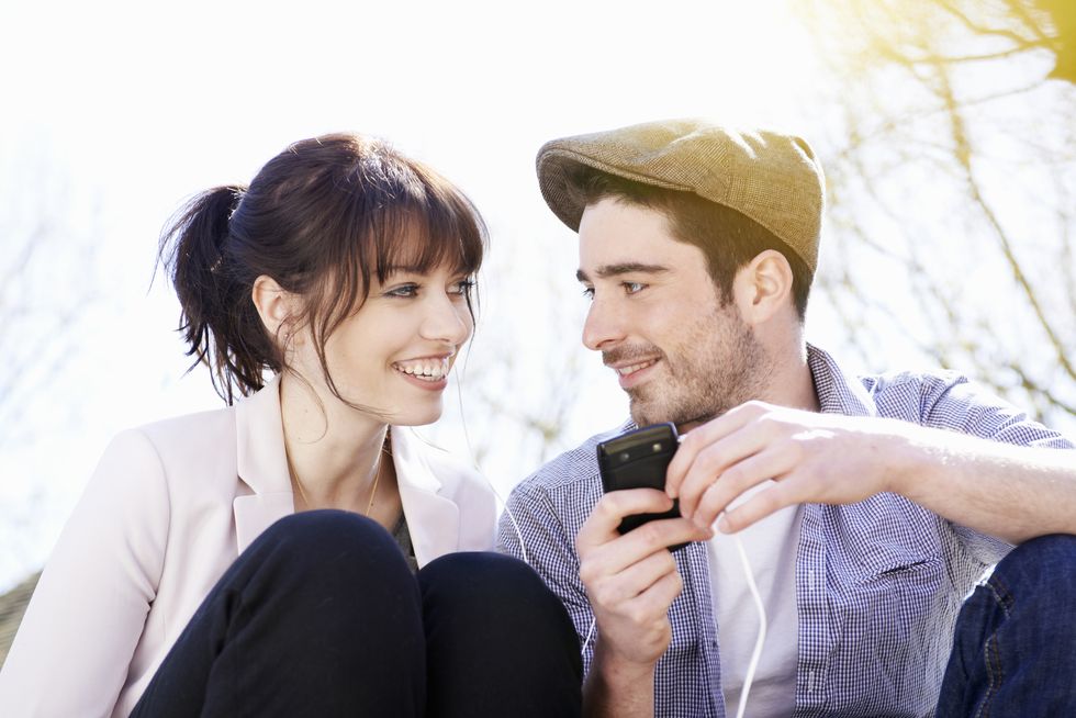 man and woman wearing headphones with mobile