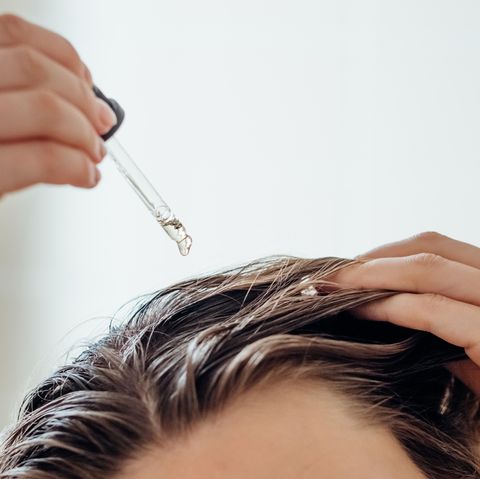 woman applies oil to her hair with pipette beauty caring for scalp and hair
