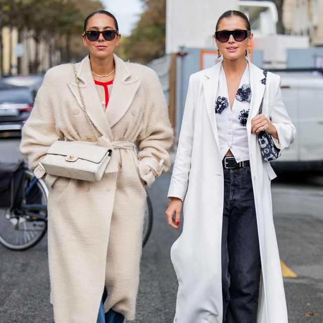 paris, france october 03 hanna mw wears creme white belted coat, bag, denim jeans darja barannik wears white coat, black white two tone boots, blouse, sunglasses dark denim jeans, black bag, golden earrings outside chanel during the womenswear springsummer 2024 as part of paris fashion week on october 03, 2023 in paris, france photo by christian vieriggetty images
