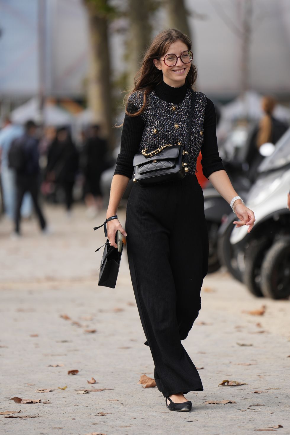 paris, france october 03 a guest wears glasses, a black turtleneck pullover, a tweed jacket with golden buttons, a black leather chanel bag, black flowing pants, flat shoes, outside chanel, during the womenswear springsummer 2024 as part of paris fashion week on october 03, 2023 in paris, france photo by edward berthelotgetty images