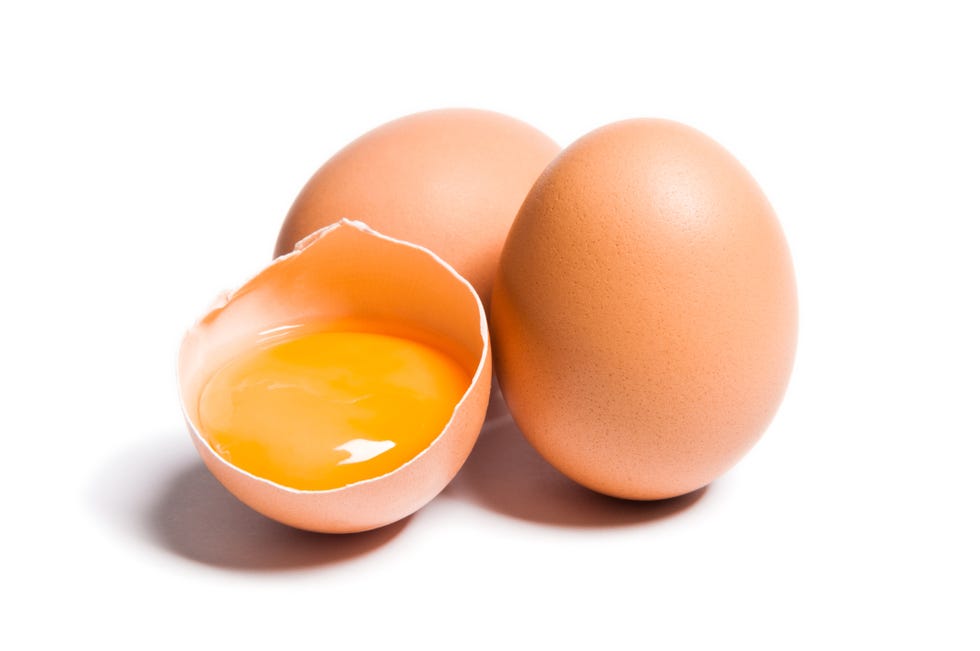 group of brown raw chicken eggs, one is broken, yolk egg visible, isolated on white, studio shot