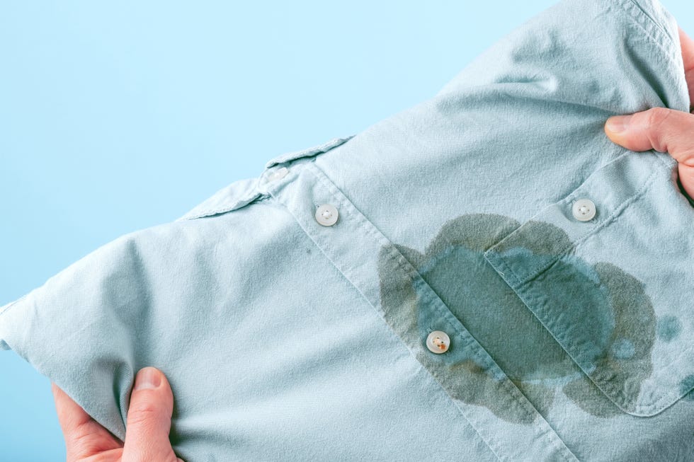 men hands showing a dirty stain shirt and visual evaluation of stain on clothes on a blue background