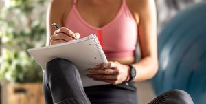 sporty woman sits on a mat and writes down future training plans for achieving sports results