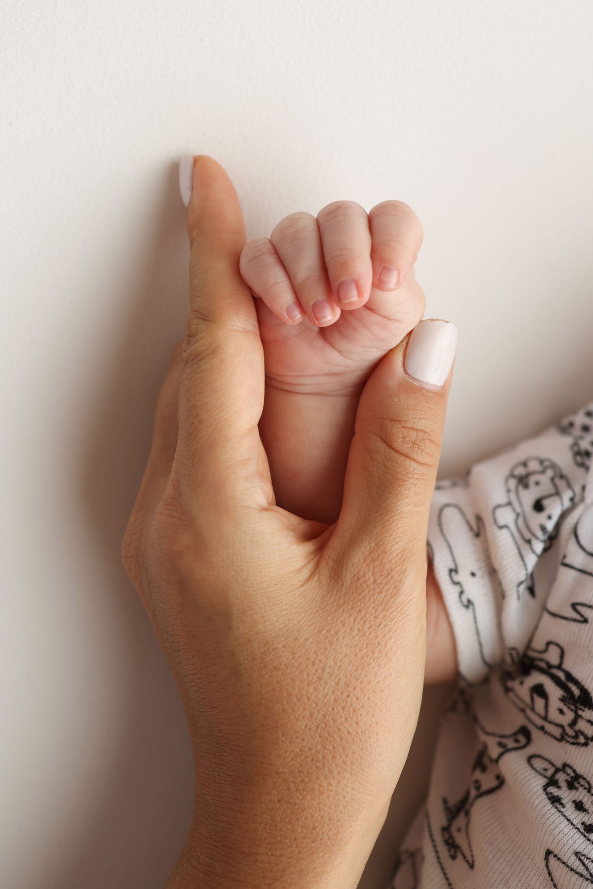 parents' hands hold the fingers of a newborn baby. the hand of a mother and father close up holds the fist of a newborn baby. family health and medical care. professional photo on white background.