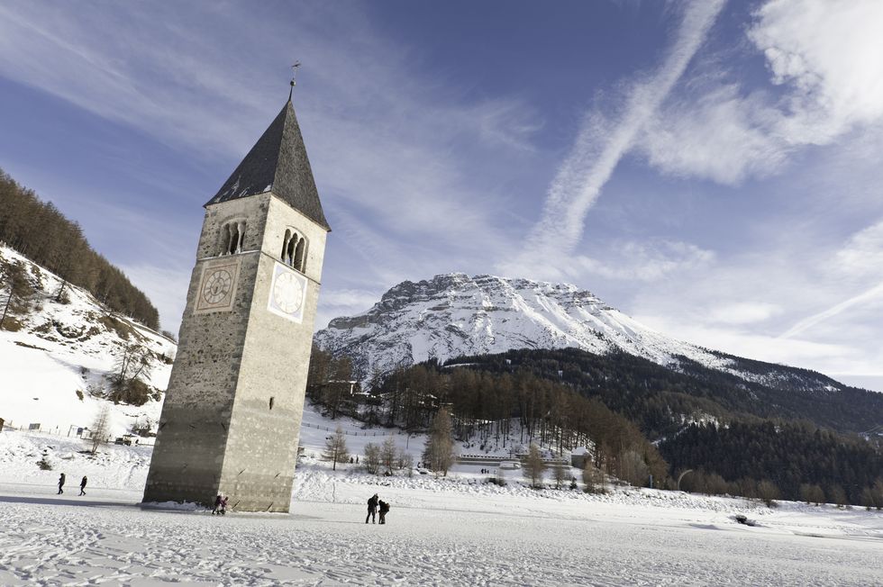 tourists walking on the frozen lake resia, on a sunny winter day