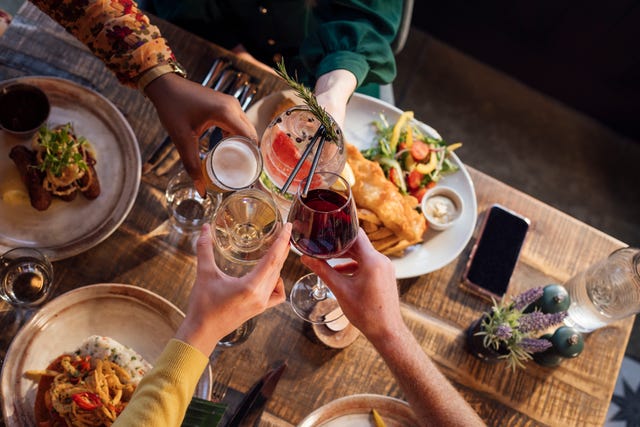 overhead view of four unrecognizable friends cheering their glasses together over the ir freshly prepared food the gastro pub is located in seahouses, northumberland
