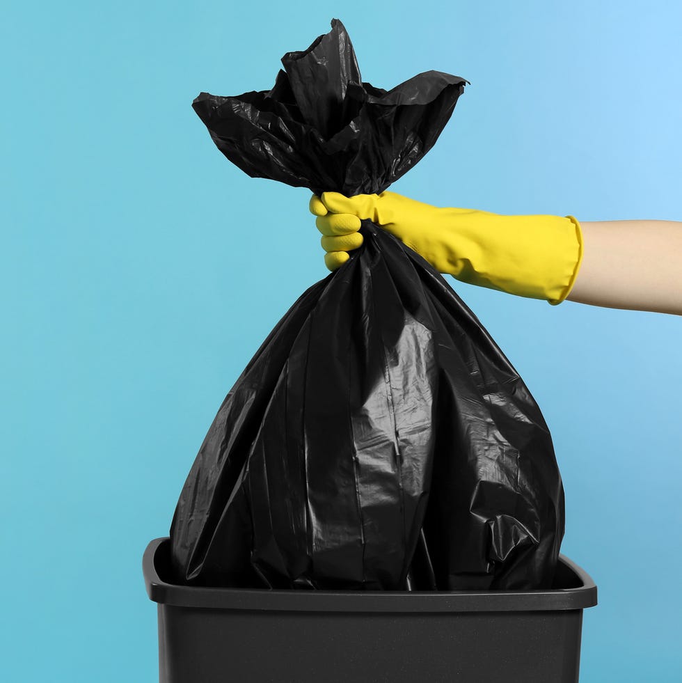 Janitor in rubber glove holding trash bag full of garbage over bucket on light blue background, closeup. Space for text janitor in rubber glove holding trash bag full of garbage over bucket on light blue background, closeup. space for text