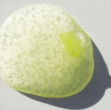 a big green drop of textured cosmetic scrub on a white background, macro