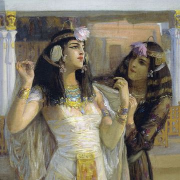 an oil painting of cleopatra, wearing a white dress and head jewelry, being tended to by a woman who puts a white veil around her