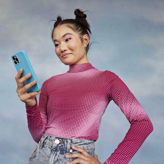 girl using mobile phone against colored background