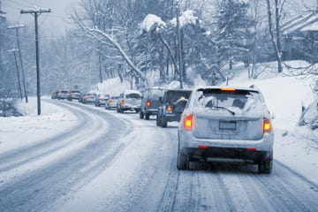 a line of cars slowly driving on a snowy, icy road