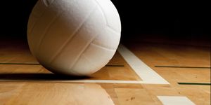 a white volleyball on the floor in a darkened gymsee my
