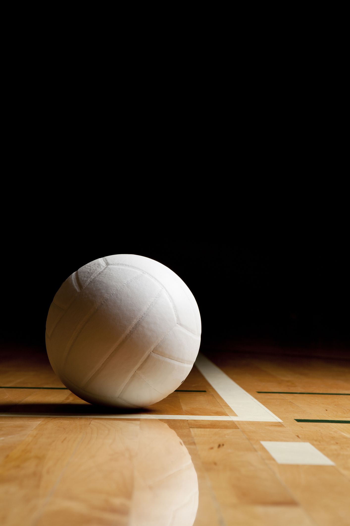 a white volleyball on the floor in a darkened gymsee my