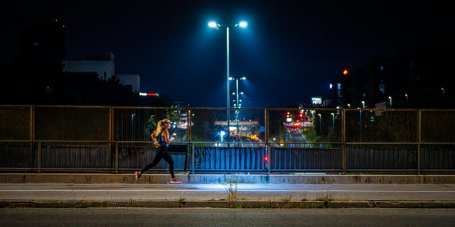 woman running at night on bridge