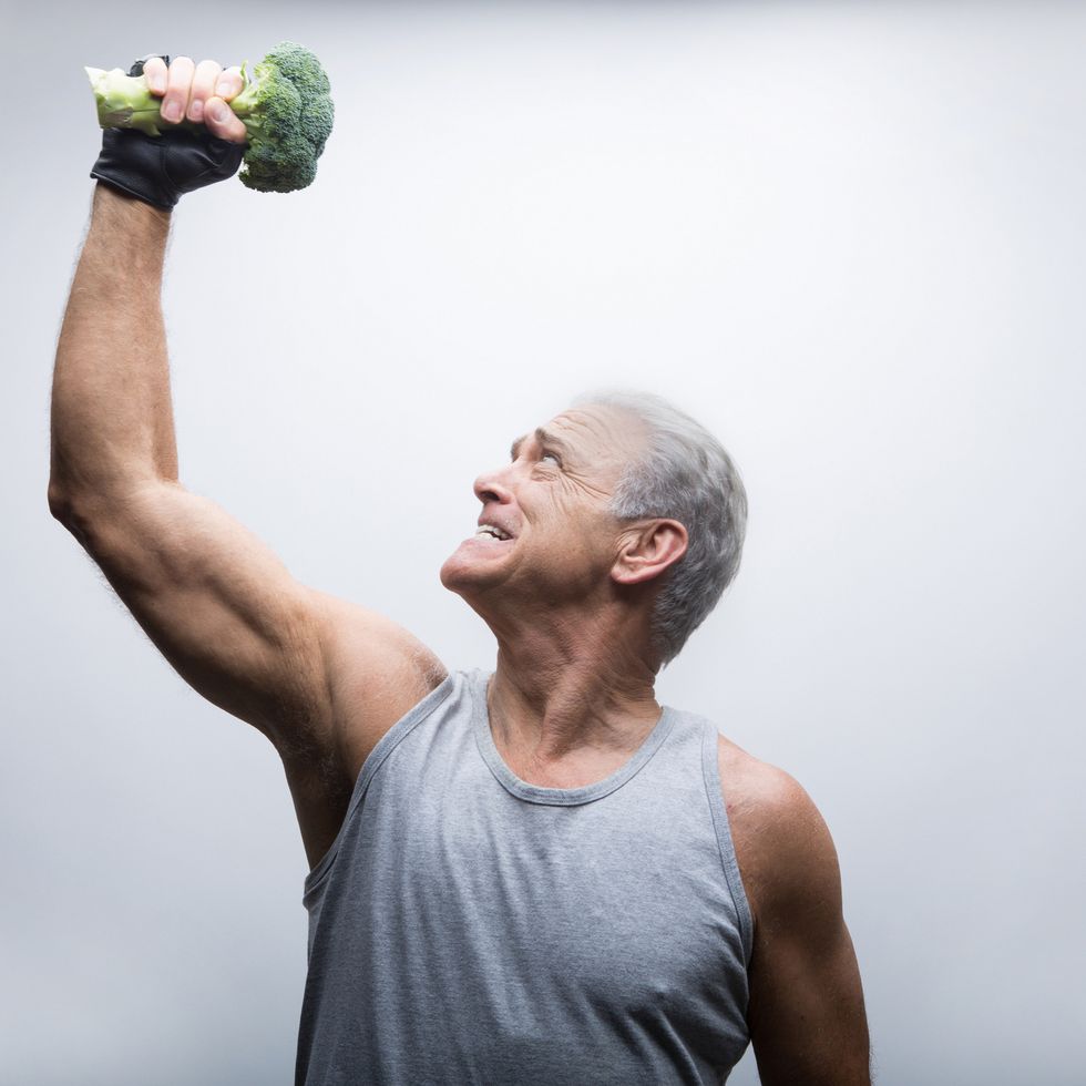 Senior man looking up and lifting broccoli