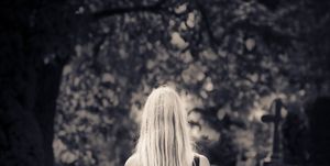Blond girl walking alone at cemetery in the dark