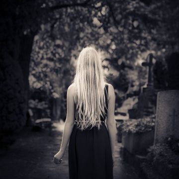 Blond girl walking alone at cemetery in the dark