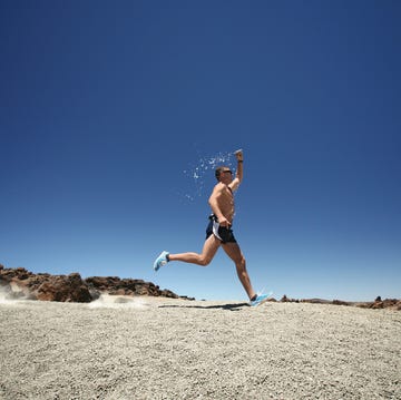 Man running on desert, drenching himself by water persona corriendo con calor y echandose agua