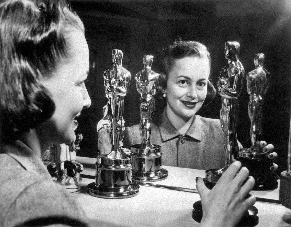 Olivia de Havilland smiling with her two Oscars, 1950s