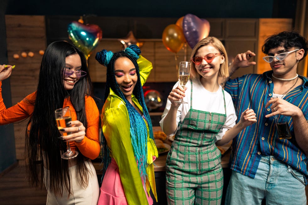 young women and men celebrating in the apartment drinking and eating, dancing and having fun