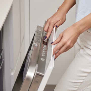 female hand turning on dishwasher machine in kitchen female hand turning on dishwasher machine in kitchen, woman choosing mode program on control panel of dishwasher