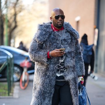 milan, italy january 13 a guest wears sunglasses, a red shirt, a gray oversized faux fur fluffy long winter coat, black pants, neon orange and yellow nike pointed sneakers shoes, a blue denim bag from telfar, outside fendi, during the milan fashion week menswear fallwinter 2024 2025 on january 13, 2024 in milan, italy photo by edward berthelotgetty images