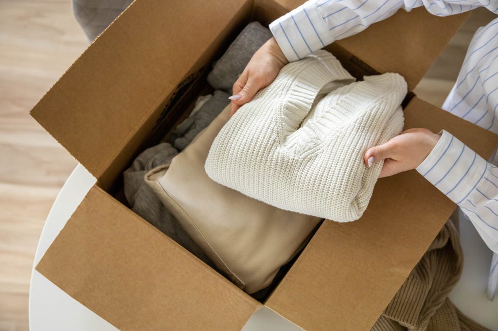 woman placing a folded sweater in a box