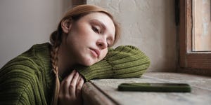 upset redhead woman sitting by window looking at mobile phone waiting call from boyfriend, feeling sad and depressed looking at smartphone waiting for sms message social media depression