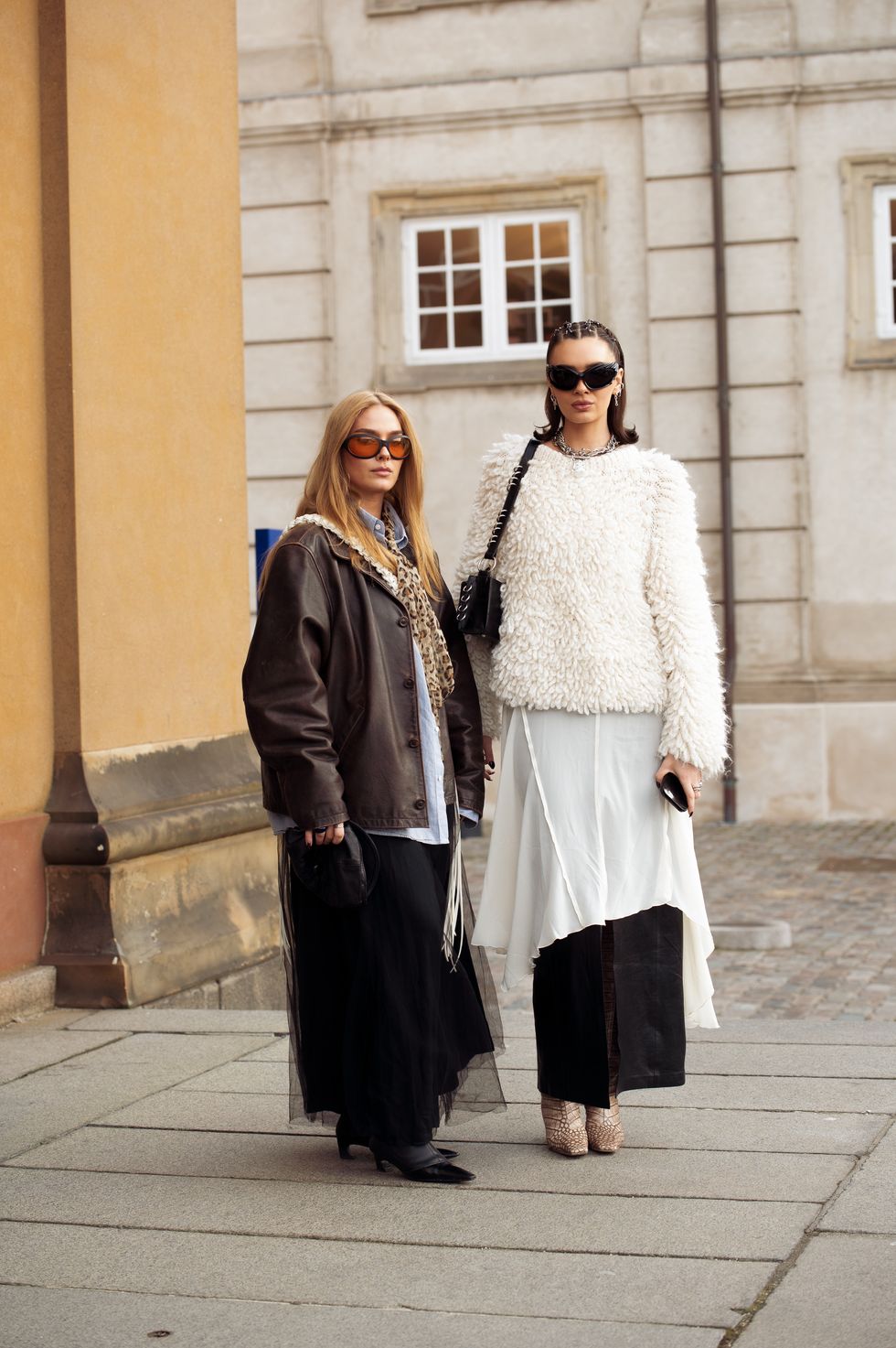 copenhagen, denmark january 29 a guest is wearing a long black tule skirt, brown leather jacket, and orange sunglasses and a guest is wearing a long black leather skirt and white tule dress, and white sweater on top during the copenhagen fashion week aw24 on january 29, 2024 in copenhagen, denmark photo by raimonda kulikauskienegetty images