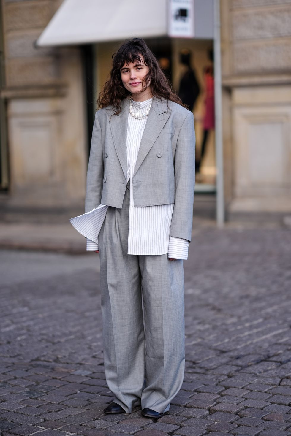 copenhagen, denmark february 01 a guest wears a white striped oversized shirt, a gray oversized blazer jacket , suit flared pants , black leather shoes, outside mark kenly domino tan, during the copenhagen fashion week aw24 on february 01, 2024 in copenhagen, denmark photo by edward berthelotgetty images