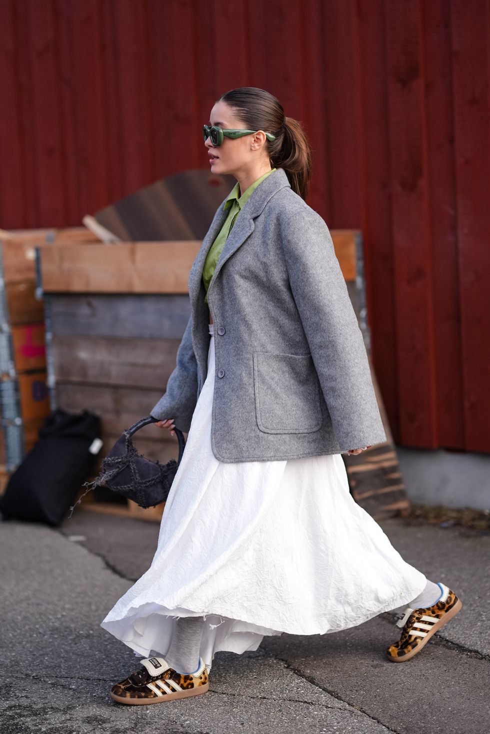 copenhagen, denmark february 01 a guest wears green sunglasses from loewe, a green shirt, a gray oversized blazer jacket , a white gathered midi dress, brown leopard print pattern adidas sneakers shoes , a black fluffy bag, outside gestuz, during the copenhagen fashion week aw24 on february 01, 2024 in copenhagen, denmark photo by edward berthelotgetty images
