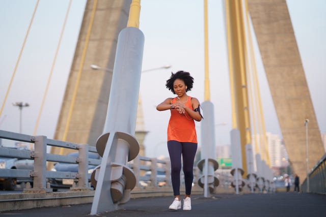 person jogging on a bridge with a large suspension structure in the background