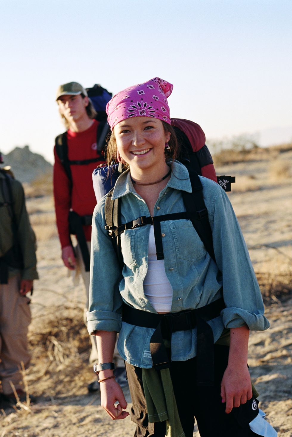Teenage girl (16-18) wearing backpack in desert with friends, portrait