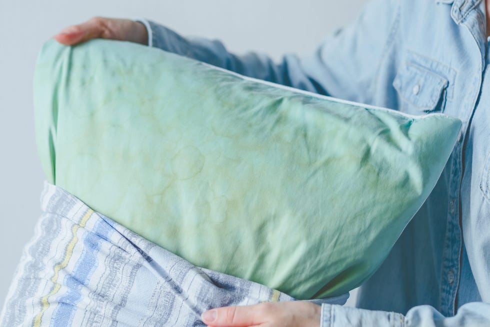female hands change a pillowcase from dirty saliva stains on a pillow for long term use