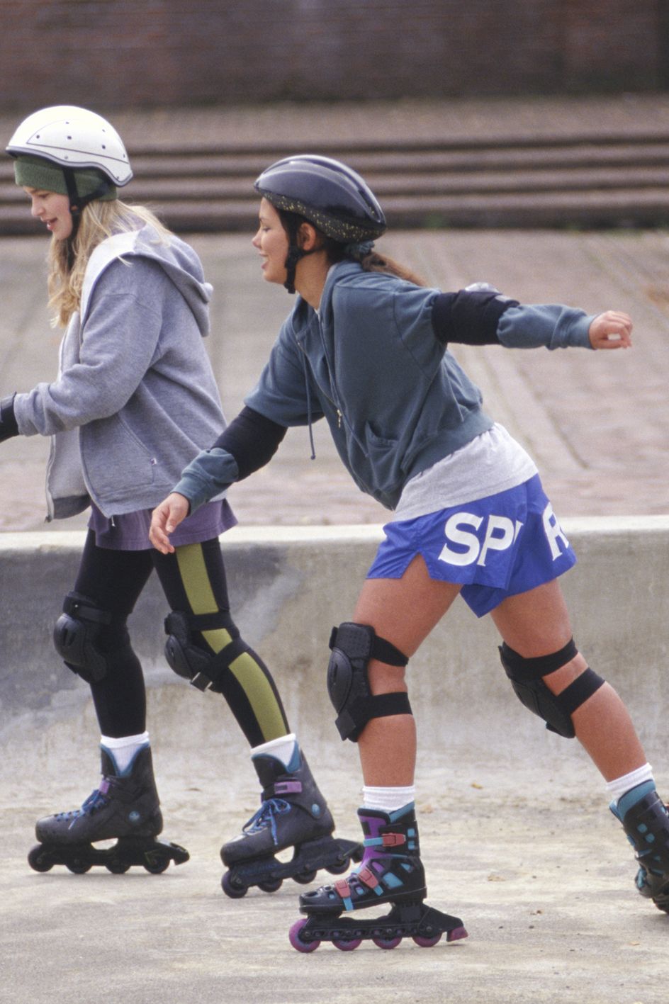 Two teenage girls (14-15) inline skating in park