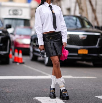 a person in a white shirt and black skirt walking across a street