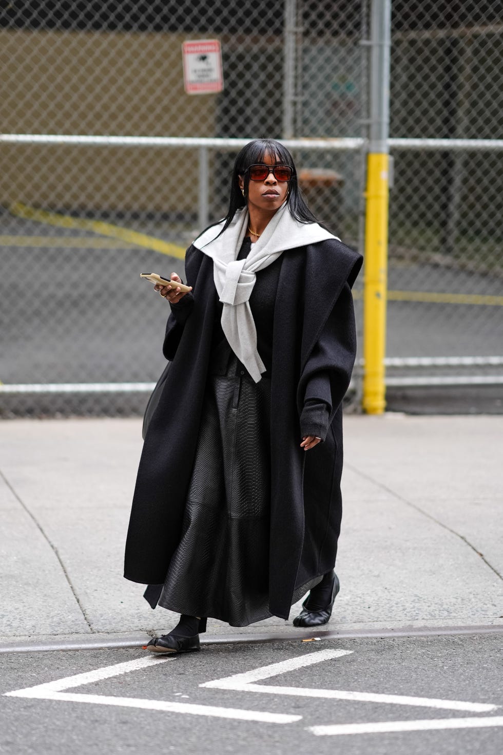 new york, new york february 11 a guest wears sunglasses, a gray pullover , a black oversized long coat, a black leather skirt, flat ballerina shoes, outside area, during new york fashion week, on february 11, 2024 in new york city photo by edward berthelotgetty images