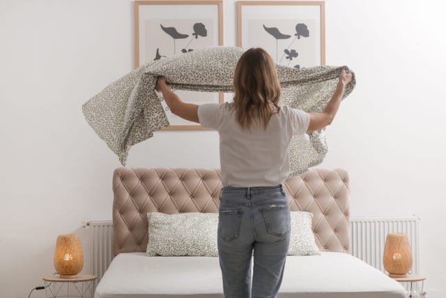 woman changing bed linens at home in her bedroom, cozy domestic lifestyle, housewife cleaning, tidying up bedroom, housework concept.