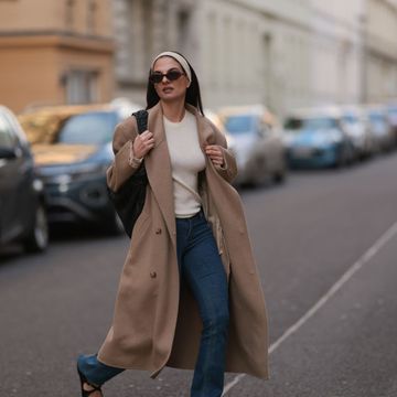 berlin, germany february 25 anna winter seen wearing brown tortoise oval sunglasses, raey creamy white basic shirt, matching creamy white hair band, source unknown beige overside wool long coat, rotate dark blue skinny jeans  denim pants, bottega veneta black leather woven jodie bag and bally black varnished leather ballerinas, on february 25, 2024 in berlin, germany photo by jeremy moellergetty images