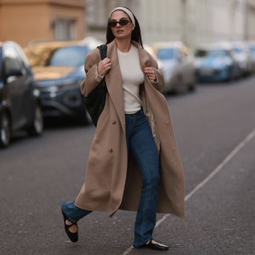 berlin, germany february 25 anna winter seen wearing brown tortoise oval sunglasses, raey creamy white basic shirt, matching creamy white hair band, source unknown beige overside wool long coat, rotate dark blue skinny jeans  denim pants, bottega veneta black leather woven jodie bag and bally black varnished leather ballerinas, on february 25, 2024 in berlin, germany photo by jeremy moellergetty images