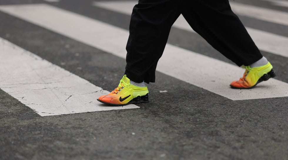 PARIS, FRANCE, FEBRUARY 27: Baggy black denim pants and orange Nike A guest was seen wearing yellow sneakers.