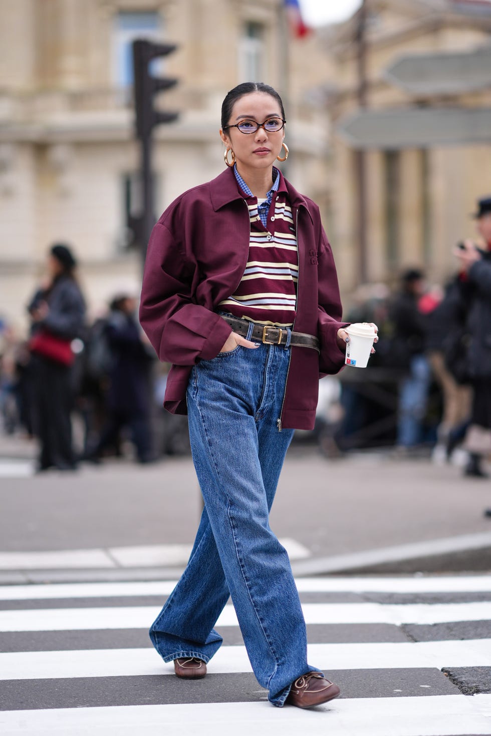 paris, france march 05 yoyo cao wears golden earrings, a burgundy oversized jacket , a striped polo shirt, a belt, blue denim pants  jeans , brown leather loafers shoes, outside miu miu , during the womenswear fallwinter 20242025 as part of paris fashion week on march 05, 2024 in paris, france photo by edward berthelotgetty images