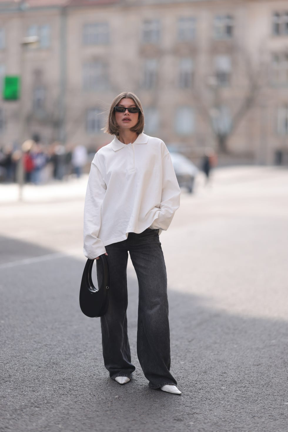 berlin, germany march 13 sophia geiss seen wearing ysl black sunglasses, cos white cotton buttoned polo sweater, drykorn grey baggy wide leg denim pants  jeans, coperni black leather bag and mango white leather kitten heels, on march 13, 2024 in berlin, germany photo by jeremy moellergetty images