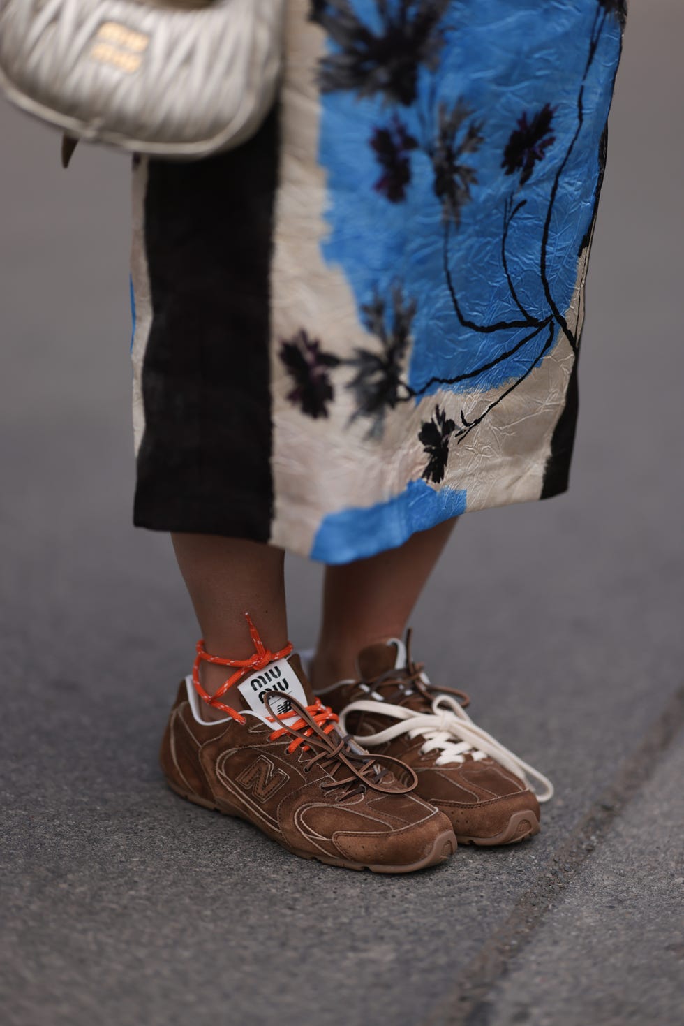 Munich, Germany - March 23, Karin Teigl wears a blue, white and black printed midi long skirt by Zara, a silver leather Wandler metallic mini bag by Miu Miu, and brown suede leather sneakers by Miu Miu x New Balance. Photo taken on March 23, 2024 in Munich, Germany: Jeremy Morraghetti Image