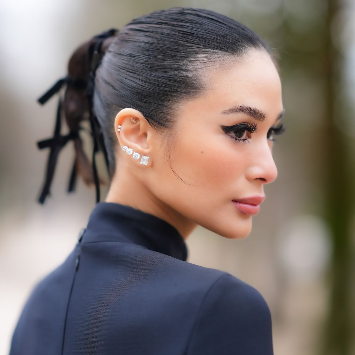 paris, france february 27 heart evangelista wears bejeweled diamond earrings, lipstick, make up , a ponytail, a turtleneck collar navy blue dress, outside dior, during the womenswear fallwinter 20242025 as part of paris fashion week on february 27, 2024 in paris, france photo by edward berthelotgetty images
