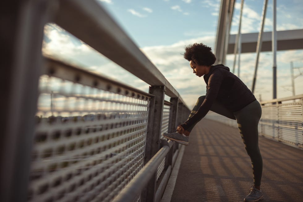 full length of fit black woman tying shoe laces african american female sport fitness runner getting ready for jogging outdoors