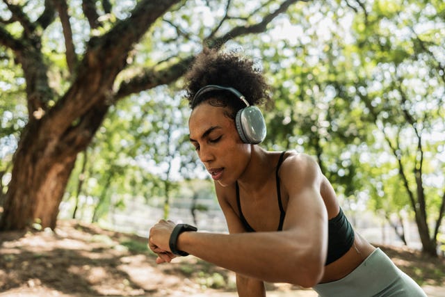 woman looking at their watch while resting from jogging outdoors