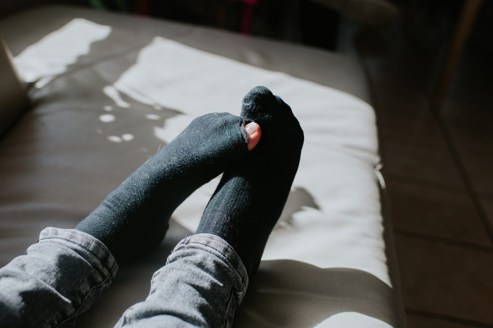 close up of person wearing socks with a hole in the big toe