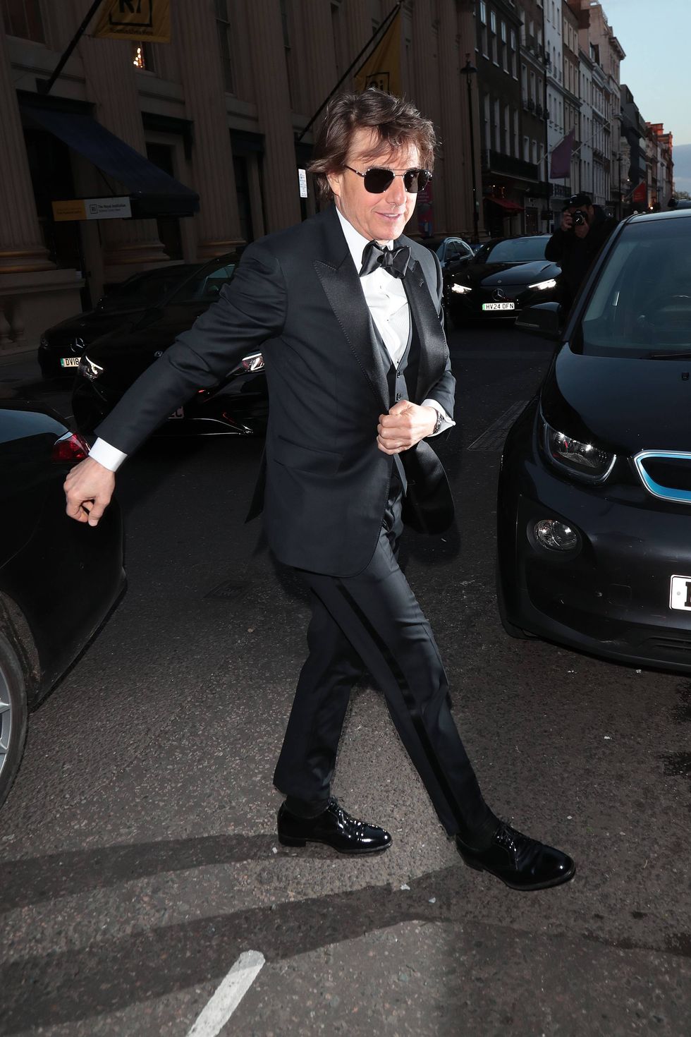 a man in a suit and sunglasses walking down a street
