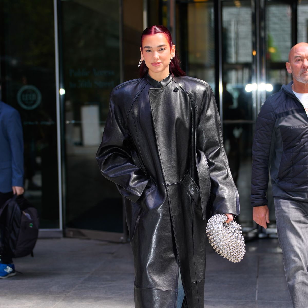 dua lipa masters the oversize trend whilst wearing an oversized leather jacket a diamond clutch bag blue jeans and black pointed heels